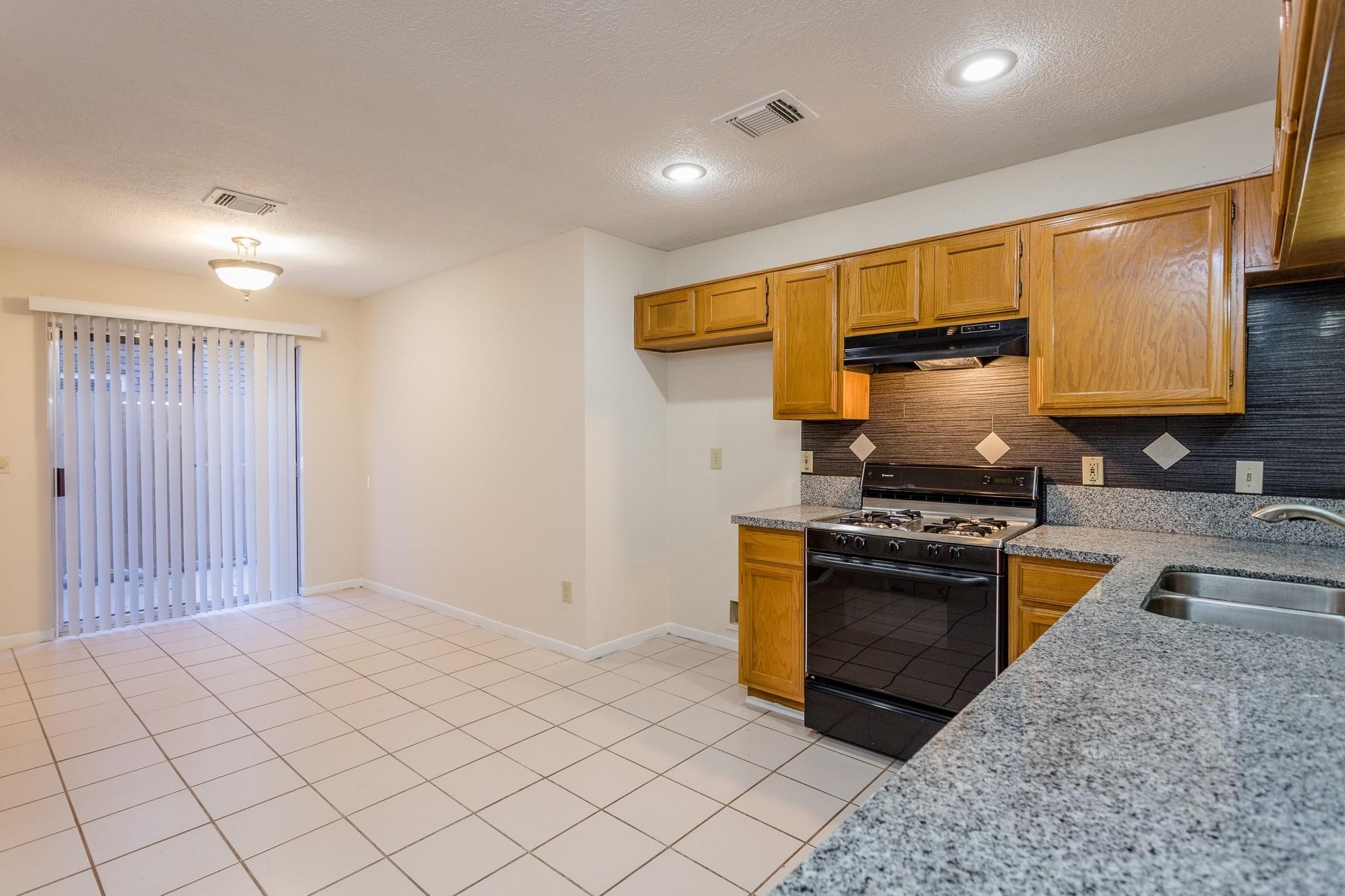9206 Towerstone Drive Spring, TX 77379 - Photo 2 of 7 a kitchen with stainless steel appliances granite countertop a stove a sink and a refrigerator