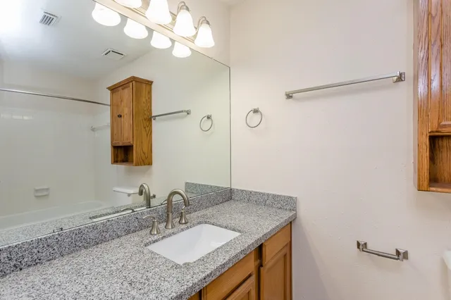 a bathroom with a granite countertop sink a mirror and shower