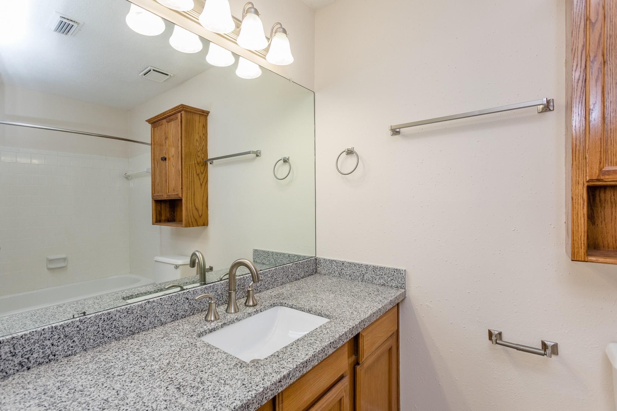 9206 Towerstone Drive Spring, TX 77379 - Photo 3 of 7 a bathroom with a granite countertop sink a mirror and shower