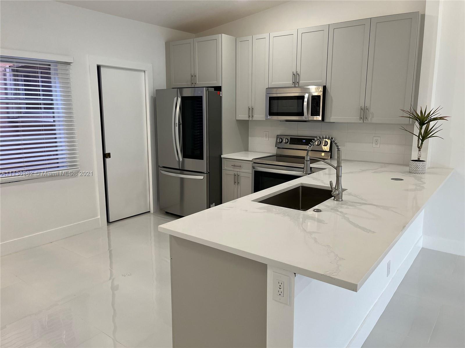 8309 Springtree Road, Unit 8309 Boca Raton, FL 33496 - Photo 5 of 18 a kitchen with a refrigerator a microwave a sink and cabinets