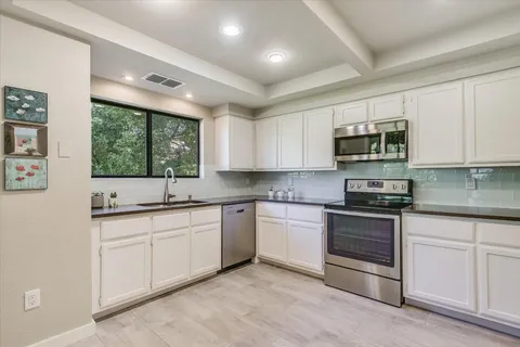 a kitchen with stainless steel appliances granite countertop a stove sink microwave and window