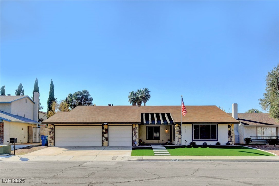 View of front facade with an attached garage, concrete driveway, and stone siding