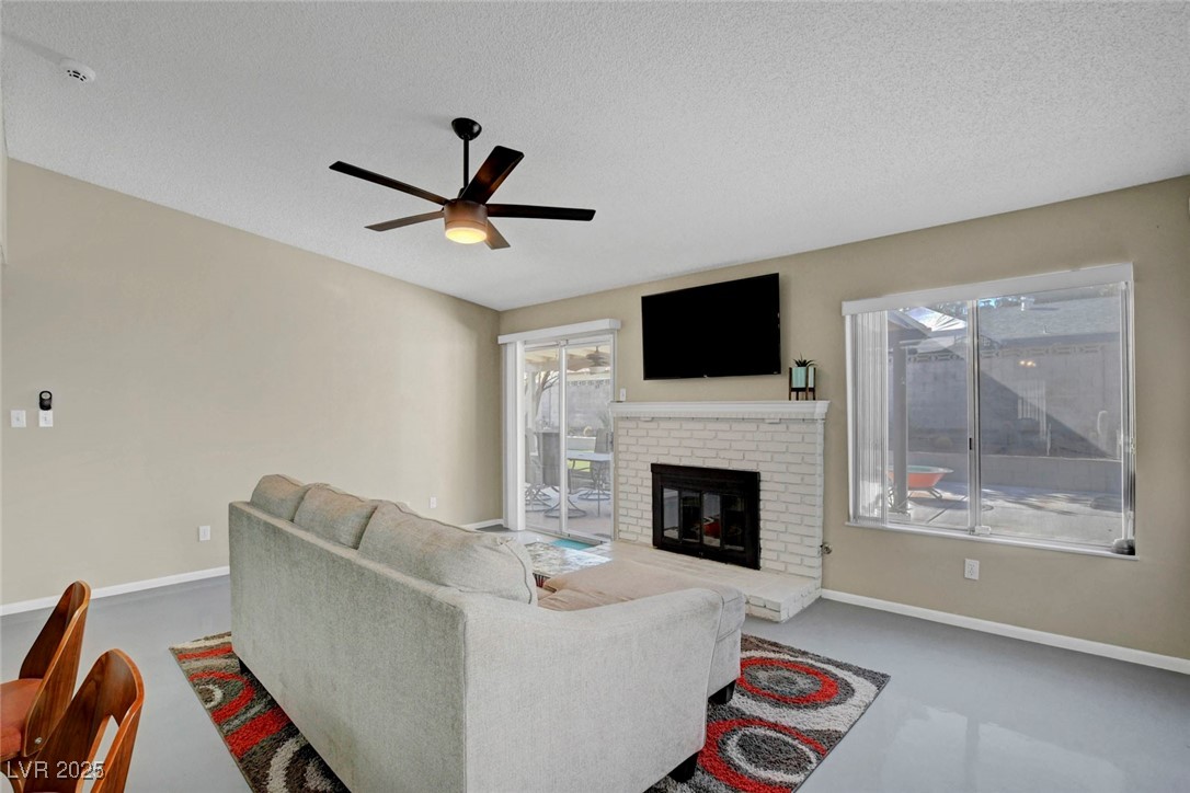3215 Mountain Spring Road Las Vegas, NV 89146 - Photo 14 of 42 Living room with a fireplace, a textured ceiling, and ceiling fan