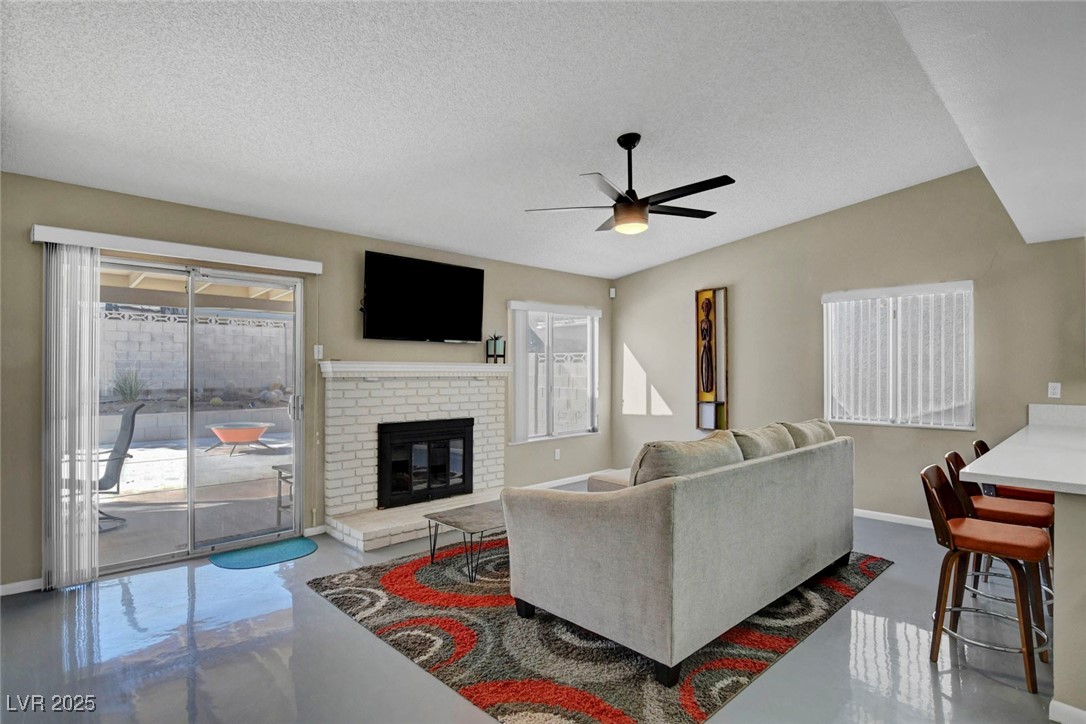 3215 Mountain Spring Road Las Vegas, NV 89146 - Photo 15 of 42 Living room with finished concrete floors, plenty of natural light, a textured ceiling, and a fireplace