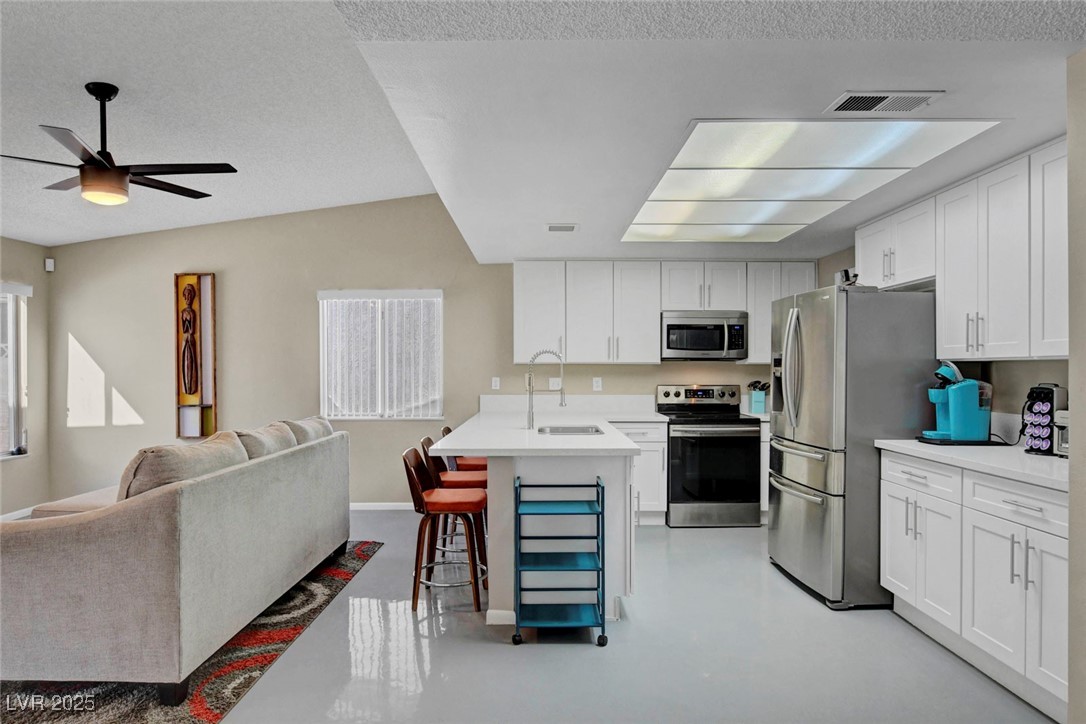 3215 Mountain Spring Road Las Vegas, NV 89146 - Photo 41 of 42 Kitchen featuring open floor plan, stainless steel appliances, a breakfast bar area, white cabinets, and finished concrete flooring
