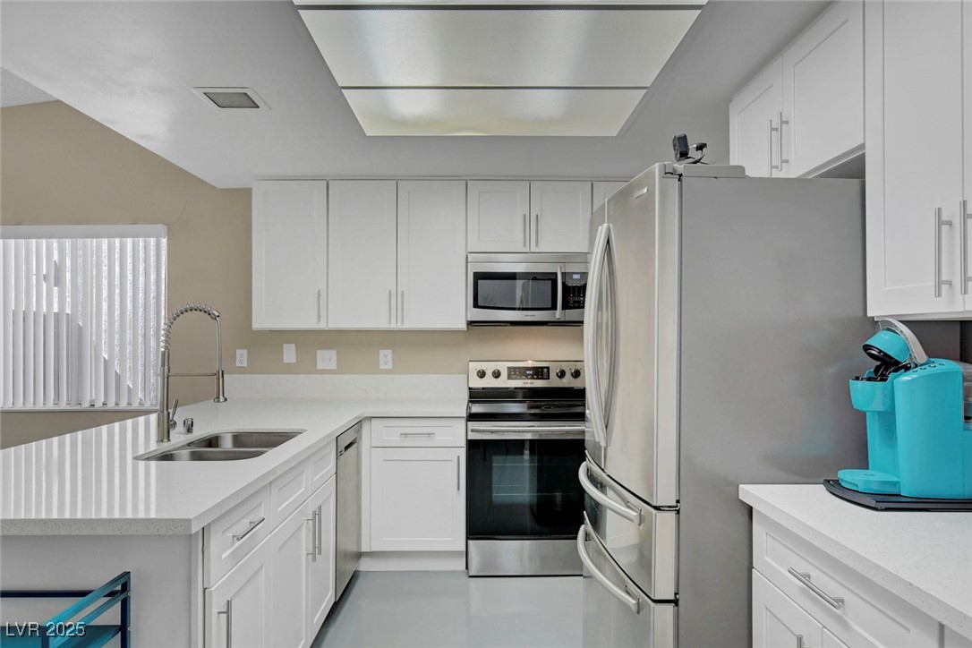 3215 Mountain Spring Road Las Vegas, NV 89146 - Photo 17 of 42 Kitchen with appliances with stainless steel finishes, white cabinetry, a peninsula, and light stone counters
