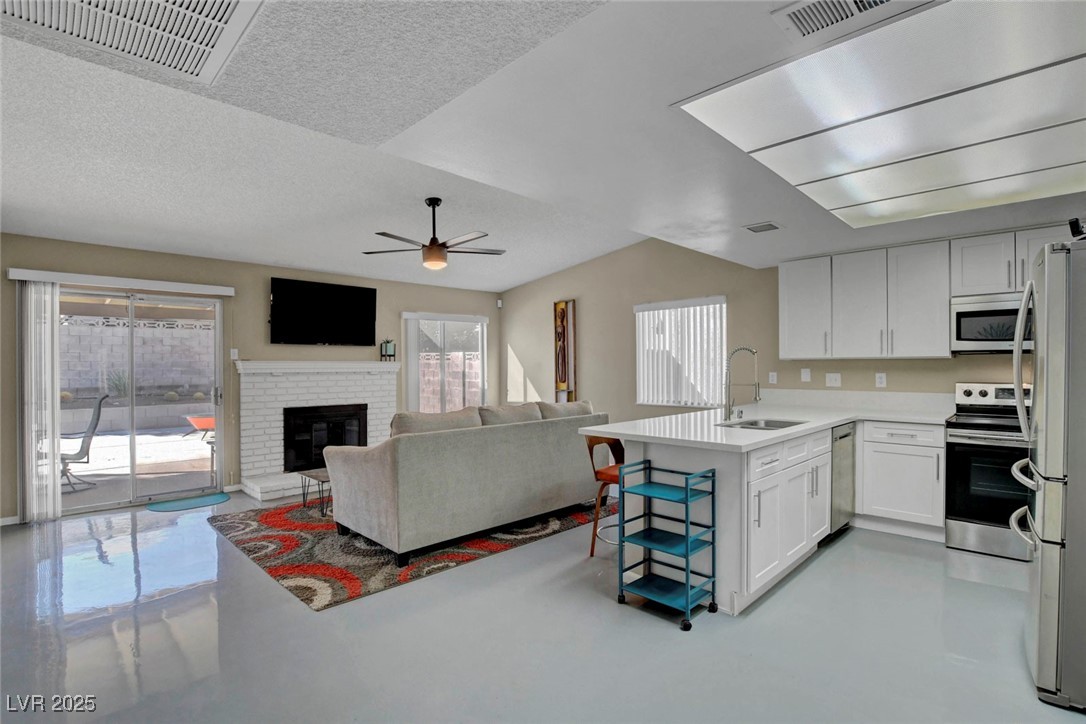 3215 Mountain Spring Road Las Vegas, NV 89146 - Photo 18 of 42 Kitchen with concrete flooring, a peninsula, white cabinetry, stainless steel appliances, and a textured ceiling