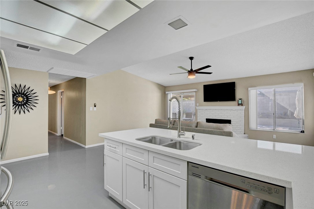 3215 Mountain Spring Road Las Vegas, NV 89146 - Photo 42 of 42 Kitchen featuring dishwasher, a fireplace, open floor plan, concrete flooring, and white cabinets