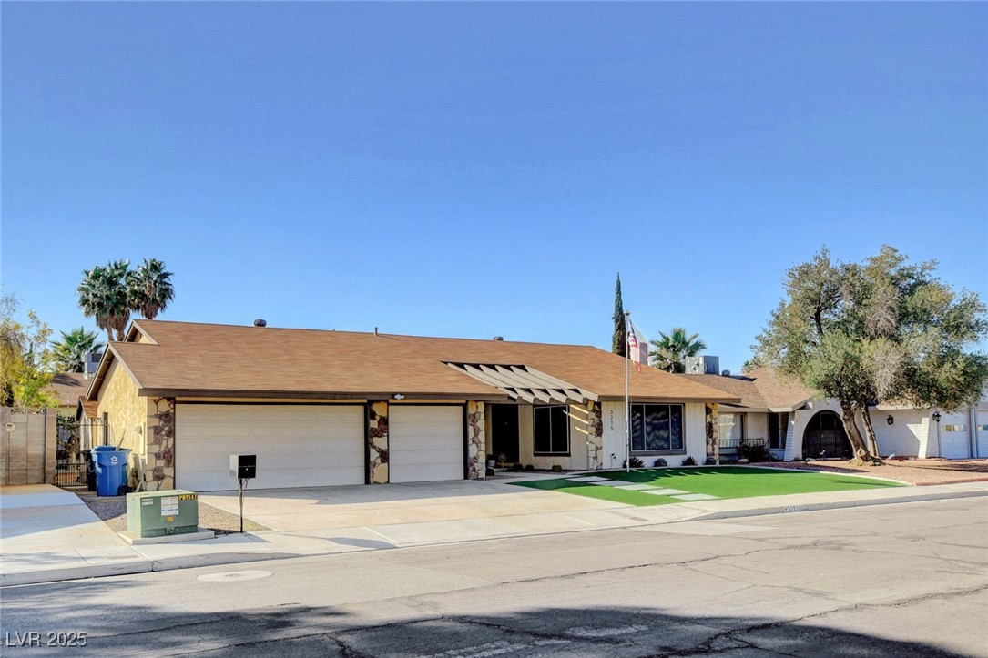 3215 Mountain Spring Road Las Vegas, NV 89146 - Photo 3 of 42 Single story home featuring concrete driveway, a garage, a shingled roof, and stone siding