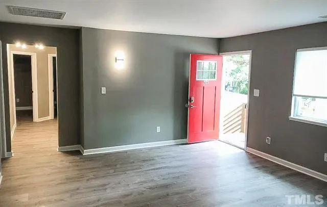 an empty room with wooden floor and windows