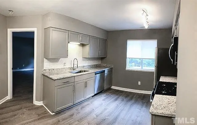 a kitchen with granite countertop a sink cabinets and a wooden floor