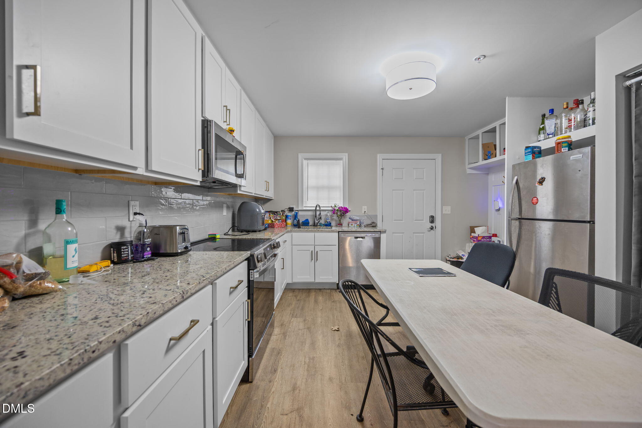 1508 Gorman Street, Unit 102 Raleigh, NC 27606 - Photo 6 of 25 a kitchen with granite countertop a refrigerator a sink dishwasher a stove and white cabinets with wooden floor