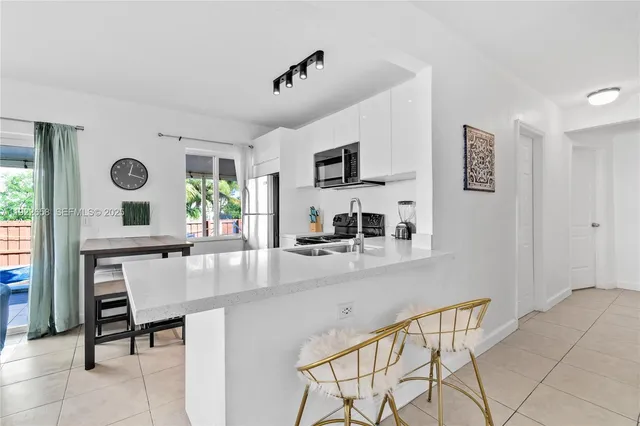 a kitchen with kitchen island granite countertop a stove a sink a microwave and a dining table with wooden floor