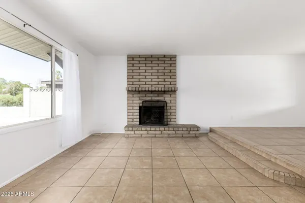 a view of an empty room with a fireplace and a window