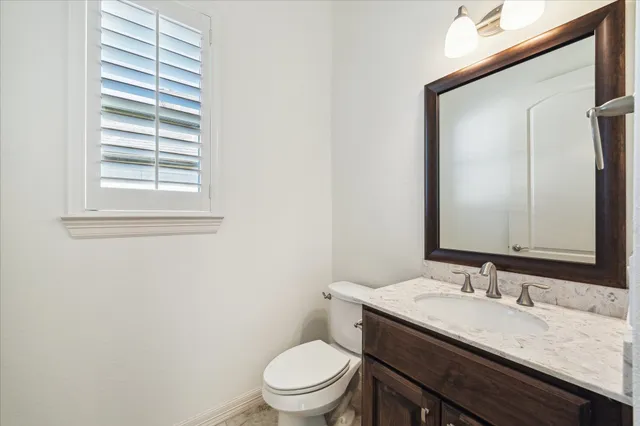 a bathroom with a granite countertop sink toilet and mirror