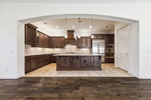 a large white kitchen with kitchen island a sink stainless steel appliances and cabinets
