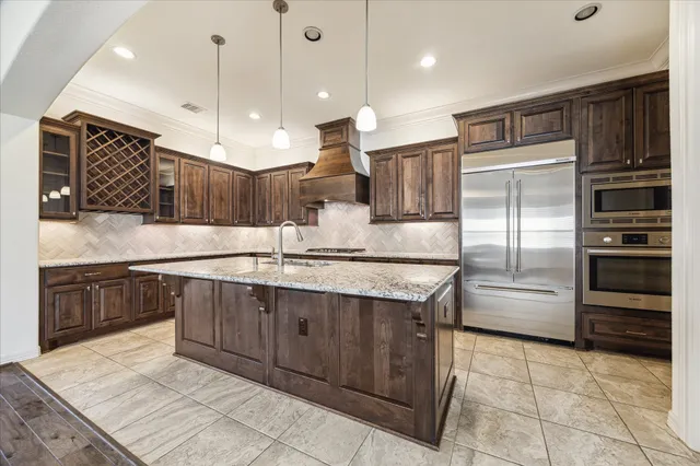 a large kitchen with a large counter top stainless steel appliances and cabinets