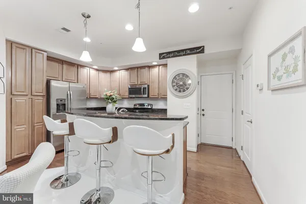 a kitchen with stainless steel appliances granite countertop a sink a stove a refrigerator cabinets and chairs
