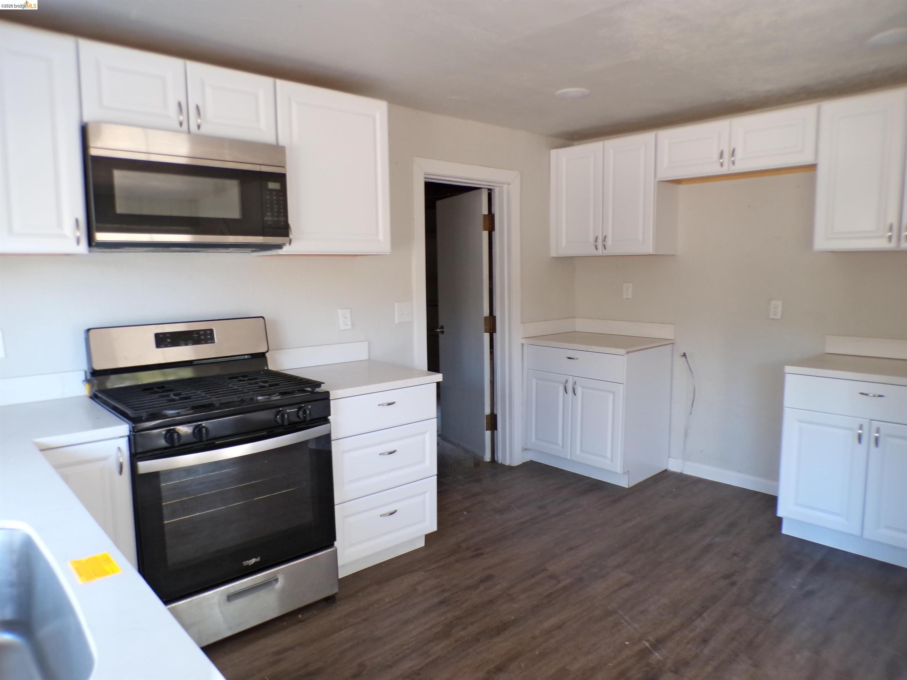 4271 Council Trail Copperopolis, CA 95228 - Photo 16 of 32 Kitchen featuring new stainless steel appliances, white cabinetry, light-toned countertops, and wood-finish flooring