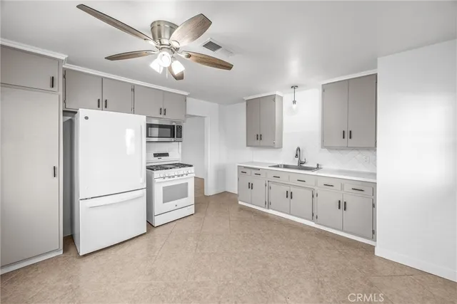 a large white kitchen with cabinets stainless steel appliances and a chandelier