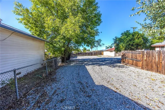 a view of a backyard with wooden fence and large trees