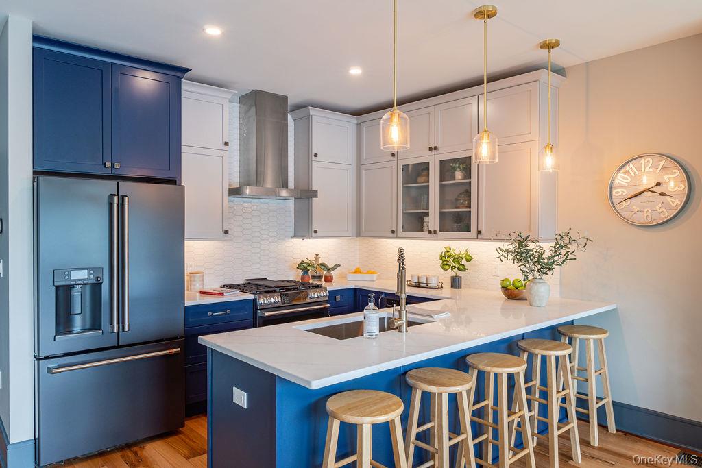 4 Icehouse Drive Saugerties, NY 12477 - Photo 12 of 34 Kitchen with a kitchen bar, high end appliances, blue cabinets, wall chimney range hood, and glass insert cabinets