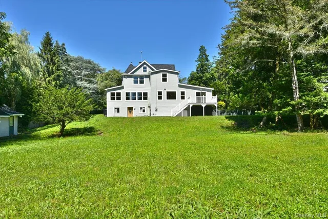 a white house with a big yard and large trees