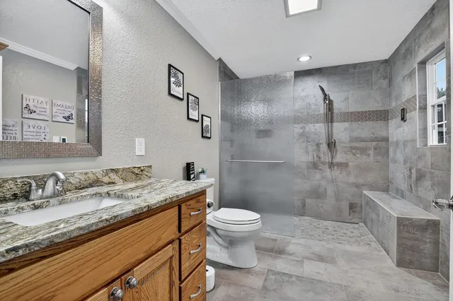 a bathroom with a granite countertop sink a toilet and shower