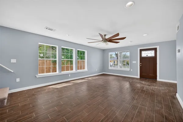 a view of an empty room with a window and wooden floor