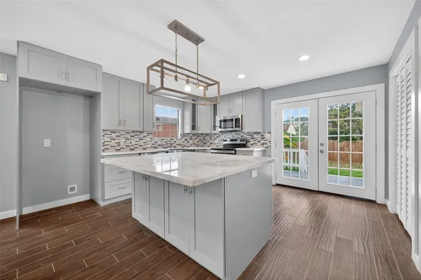 a kitchen with granite countertop a stove a sink wooden floor and cabinets