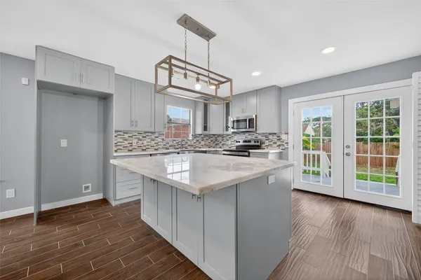 a kitchen with stainless steel appliances granite countertop a sink a stove a refrigerator cabinets and wooden floor