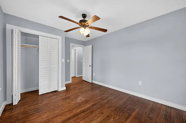 an empty room with wooden floor closet and fan