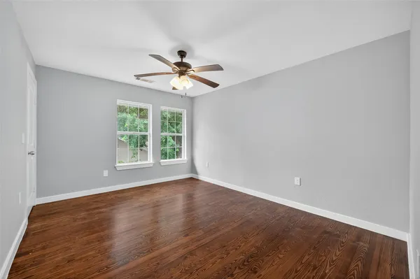 a view of an empty room with a window and wooden floor