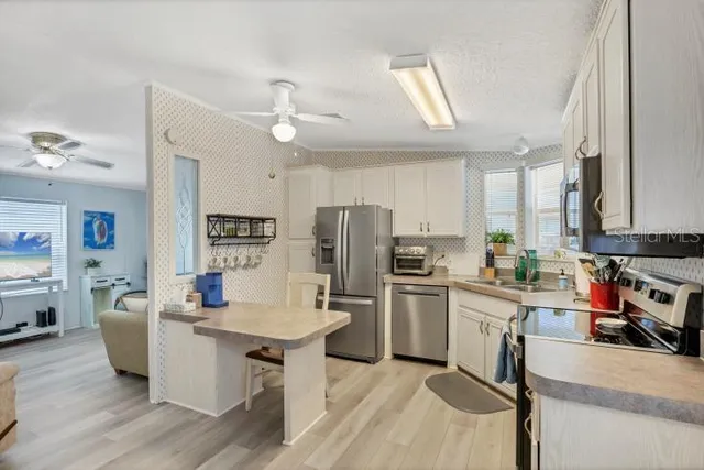 a kitchen with stainless steel appliances a sink a stove a refrigerator cabinets and living room view