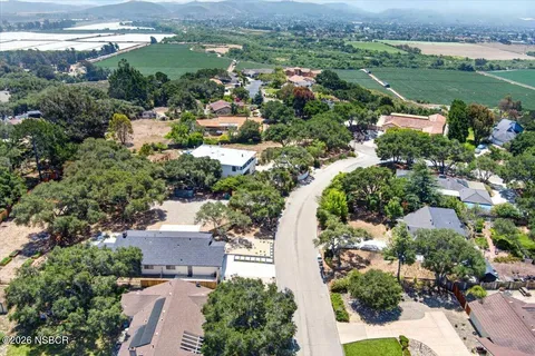 an aerial view of residential houses with outdoor space and trees