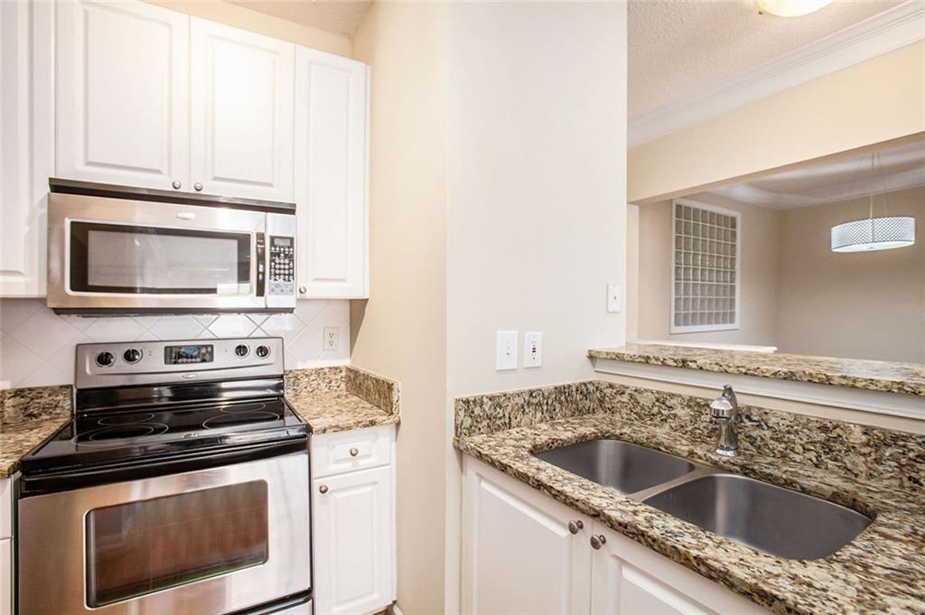 10 Perimeter Summit Boulevard, Unit 3301 Atlanta, GA 30319 - Photo 8 of 36 a kitchen with granite countertop a stove sink and microwave