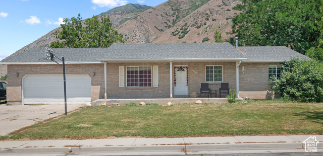 1669 East 300 South Springville, UT 84663 - Photo 1 of 1 Ranch-style home with covered porch, a front yard, driveway, a garage, and brick siding
