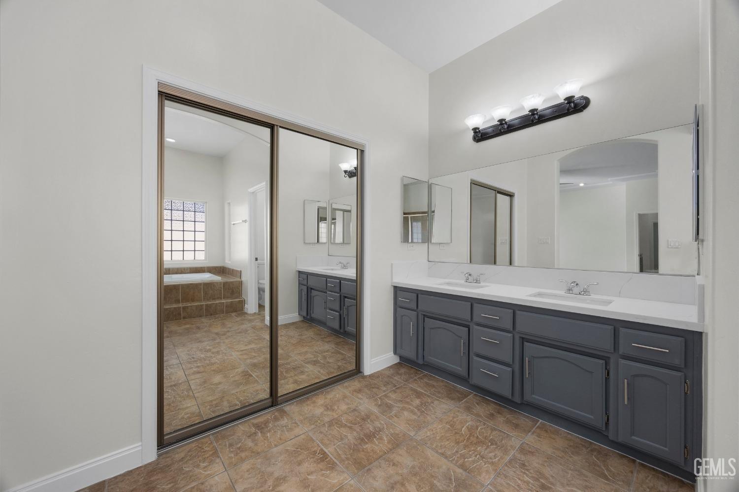 Undisclosed Address Bakersfield, CA 93313 - Photo 31 of 44 a spacious bathroom with a double vanity sink and a mirror