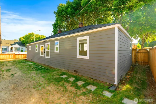 a view of a backyard with plants and large tree