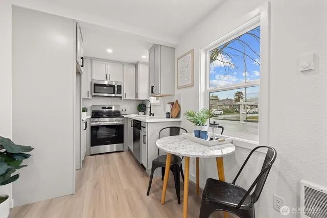a kitchen with kitchen island a dining table chairs stainless steel appliances and windows
