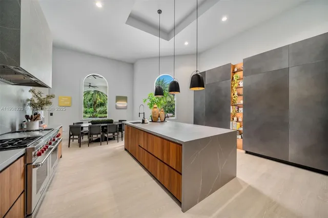 a kitchen with stainless steel appliances a stove a chimney a refrigerator and a dining table