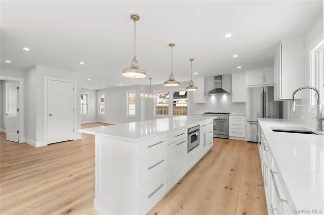 a large kitchen with stainless steel appliances kitchen island a large counter top a sink a stove and a wooden floors