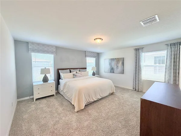 a spacious bedroom with a bed and wooden floor