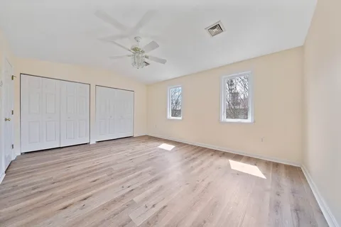 a view of an empty room with a window and wooden floor