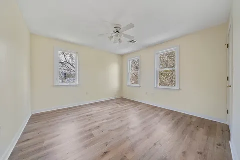 an empty room with windows and fan
