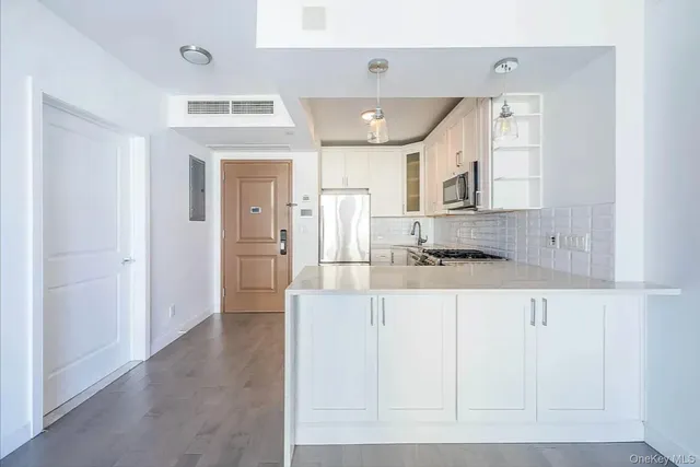 a large white kitchen with kitchen island a sink stainless steel appliances and cabinets