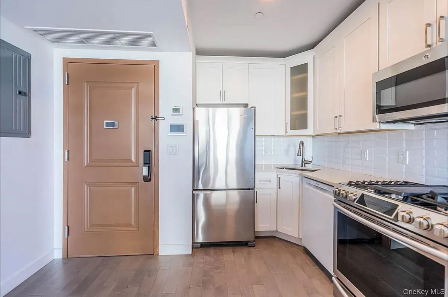 41-04 27th Street, Unit 9A Queens, NY 11101 - Photo 4 of 14 a kitchen with a refrigerator stove and wooden cabinets