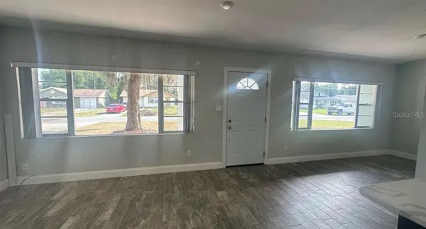 an empty room with wooden floor and windows