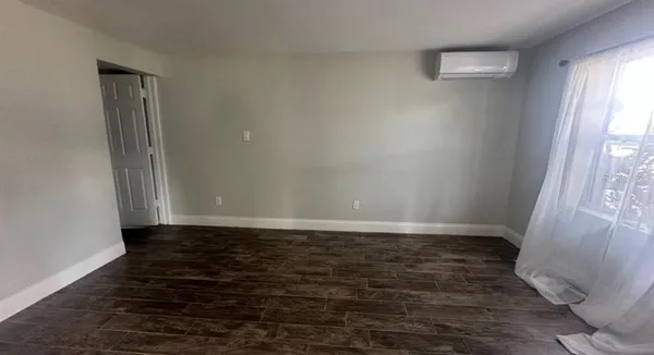 a view of an empty room with wooden floor and a window