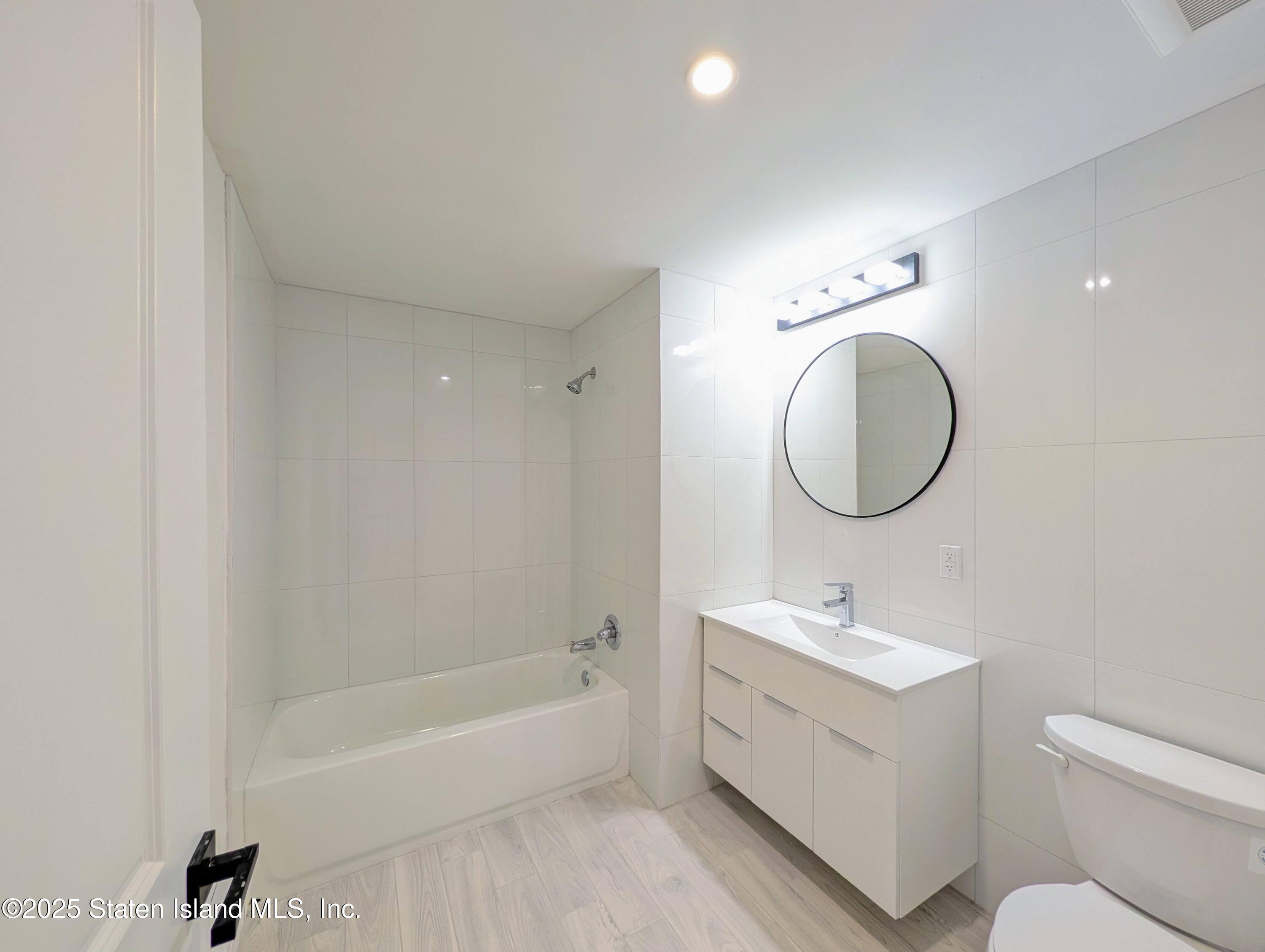 3865 Amboy Road, Unit 4D Staten Island, NY 10308 - Photo 21 of 30 a bathroom with a toilet sink a mirror and a bathtub